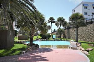 a swimming pool with a chair and palm trees at New Listing! Beautiful 1/1 Condo with Gorgeous Beach Views! Pool & Hot Tub!! - Shell We Dance in Galveston
