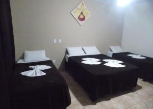 a room with two beds with black sheets and white pillows at Pousada Aldeia das Flores in Olímpia +24 photos