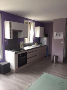 a kitchen with white appliances and purple walls at La maison parisienne maison deux pièces à louer au pied du métro in Maisons-Alfort