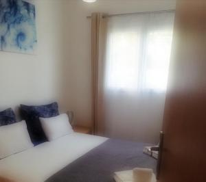 a bedroom with a white bed and a window at Apartman Nada in Kornić