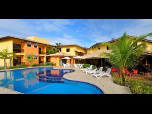a resort with a swimming pool and chairs and a building at Porto Geraes Praia Hotel in Porto Seguro