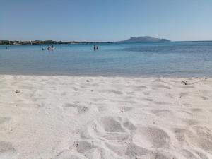 una playa de arena con gente nadando en el agua en Olbia Center House, en Olbia