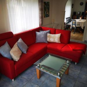 um sofá vermelho com almofadas e uma mesa de café de vidro em Ferienwohnungen und Ferienhaus im Nixenweg em Hohwacht