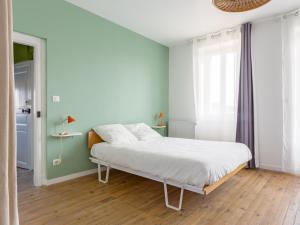una camera da letto con un letto con lenzuola bianche e pareti blu di Le Passage - appartement lumineux à La Madeleine ad Albi