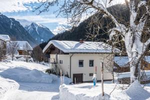 una casa en la nieve con montañas en el fondo en Haus Krömer, en Sankt Gallenkirch