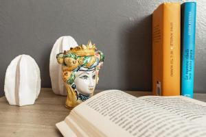 eine Vase auf einem Tisch neben einem Buch in der Unterkunft B&B Dimora dei Templi in Agrigento