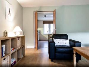 Sala de estar con silla negra y mesa en 20/5 Timber Bush, en Edimburgo