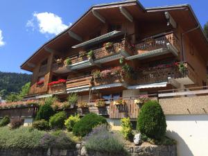 un bâtiment avec des boîtes de fleurs et des balcons. dans l'établissement Résidence Le Faber, au Grand-Bornand