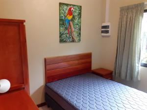 a bedroom with a bed and a picture of a parrot on the wall at Max Garden and Pool in Paramaribo +51 photos