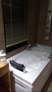Una gran cama blanca con cinturón negro. en Villa Serrana Relax & Confort, en Villa Serrana
