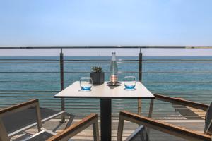 a table with two glasses and a bottle on a balcony at Villa Azur in Villeneuve-Loubet