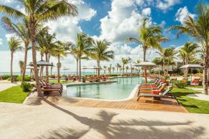 a pool at a resort with chairs and palm trees at Andaz Mayakoba All Inclusive in Playa del Carmen