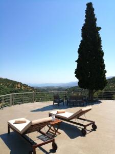 two chaise lounges on a patio with a tree at Villa Irini - Cretan Luxury Villa with Amazing View in Paraspórion