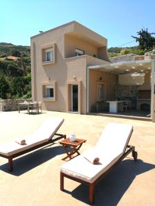 two lounge chairs on a patio in front of a house at Villa Irini - Cretan Luxury Villa with Amazing View in Paraspórion