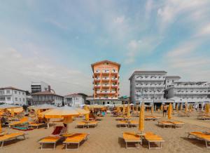 una playa con sillas y sombrillas y un edificio en Hotel Loreley, en Lido di Jesolo