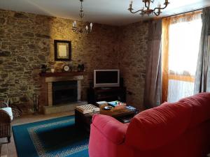 a living room with a red couch and a fireplace at A Casa do Ferrador in Vilar