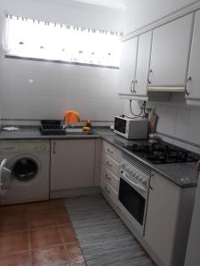 a white kitchen with a stove and a microwave at Apartamentos Arrifes 1 in Porto Santo