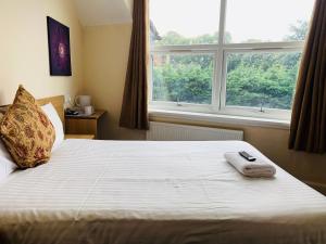 um quarto com uma cama com um controlo remoto em Albert Guest House em Kingston upon Thames