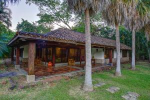 a house with a porch and two palm trees at Hacienda La Pacífica Eco-Lodge in Cañas