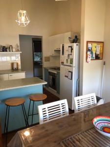 a kitchen with a refrigerator and a table and chairs at The Beach Hut Avoca Beach NSW in Avoca Beach