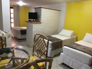 a hotel room with two beds and a tv at Pousada Laranja - Nova Administração in Natal