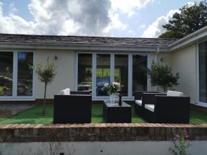 a patio with black and white furniture and windows at Couples Country Escape includes Private Indoor Pool and Hot tub in North Wales in Bagilt