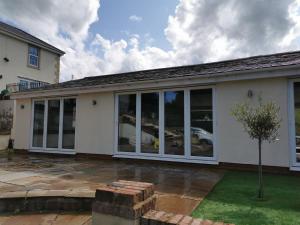 a house with large sliding glass doors at Couples Country Escape includes Private Indoor Pool and Hot tub in North Wales in Bagilt
