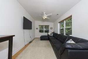a living room with a black leather couch and a flat screen tv at Harbor Delight On The Bay - Private Sandy Beach! Home in Norfolk