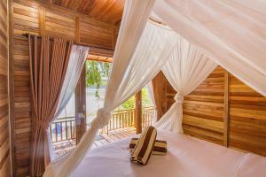 ein Schlafzimmer mit einem Himmelbett und einem Fenster in der Unterkunft Wooden Beach Sunset Cottages in Nusa Lembongan