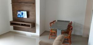 uma sala de jantar com uma mesa e uma televisão na parede em Conjunto Residencial Verdes Mares em Guaratuba