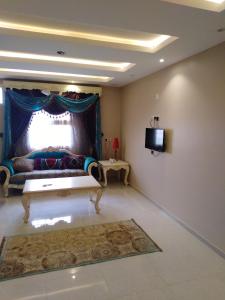 a living room with a couch and a television at Sunrise Furnished Apartment in Abha