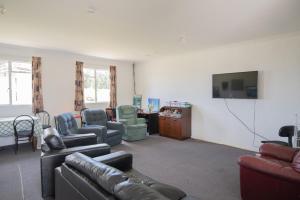 a living room with couches and chairs and a flat screen tv at beach road holiday park in Otatara