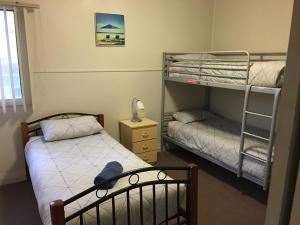 a bedroom with two bunk beds and a lamp at Kickback Cottages in Lakes Entrance