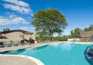 a large swimming pool with chairs and a house at Tiki Resort - Lake George in Lake George