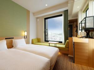 a hotel room with two beds and a large window at Candeo Hotels Osaka Kishibe in Suita +33 photos