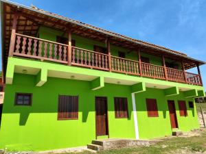 un edificio verde con un balcone in cima di Sobrado Flor de Maio a Milho Verde