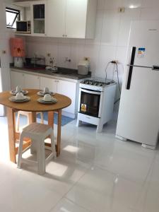 a kitchen with a table and a refrigerator at Beira Mar da Pajuçara in Maceió