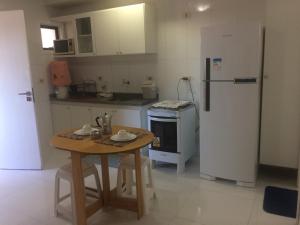 a small kitchen with a table and a refrigerator at Beira Mar da Pajuçara in Maceió