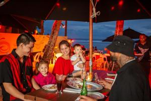 grupa ludzi siedzących przy stole jedzących jedzenie w obiekcie Castaway Resort w mieście Rarotonga