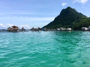 a large body of water with houses and a mountain at Suhana HomeStay Semporna - Cozy Home in Semporna