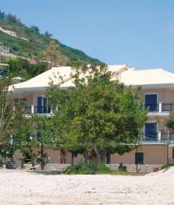 un edificio sulla spiaggia con un albero di fronte di Maistrali a Vassiliki