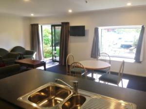 a kitchen with a sink and a living room at Woodlands Motels And Apartments in Dunedin