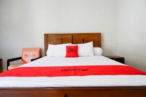 パルにあるRedDoorz near Mutiara SIS Al Jufrie Airport Paluのベッド(上に赤い枕付)