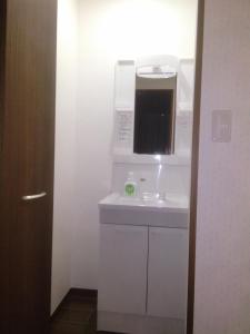 a kitchen with a microwave above a white sink at Nice Hostel Yahiro in Tokyo