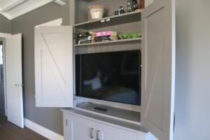 a living room with a tv in a white cabinet at Luxurious Escape,Matakana in Matakana