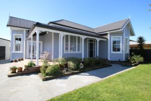 a blue house with a lawn in front of it at AristaAir- Poppies Luxury Villa in Rotorua
