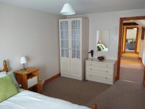 Swallow cottage في لاوث: غرفة نوم بسرير وخزانة ومرآة