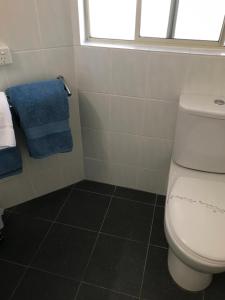 baño con aseo y toalla azul en Fairway Motor Inn, en Merimbula