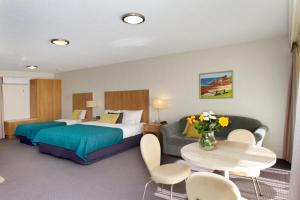 a hotel room with a bed, table and chairs at Fairway Motor Inn in Merimbula