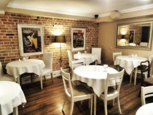 a restaurant with white tables and chairs and a brick wall at American House Hennela in Warsaw +25 photos